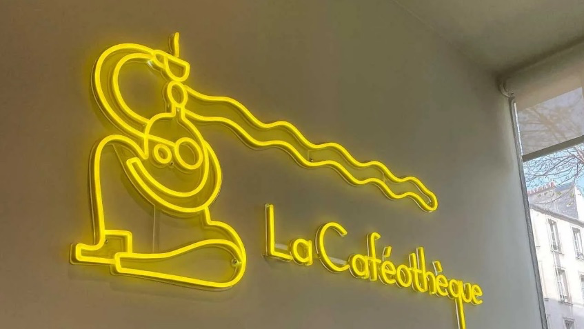 Enseigne néon jaune La Caféothèque dans le salon de Reid Hall, à Montparnasse